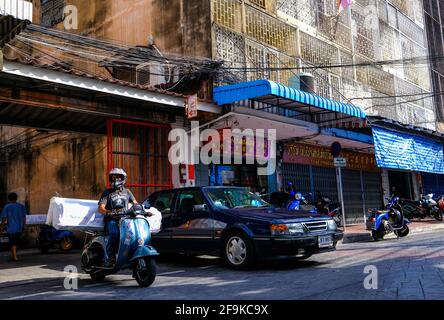 Un uomo trasporta una grande partita di merci sul retro del suo scooter Vespa a Chinatown, Bangkok, Thailandia. Foto Stock