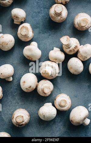 Funghi freschi champignons su sfondo blu, vista dall'alto. Foto Stock