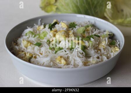 Riso basmati al vapore con uova strapazzate e cipolle primaverili, detto riso all'uovo. Scatto su sfondo bianco Foto Stock