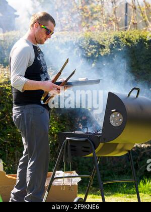 Uomo che cucina su un barbecue, Cornovaglia, Regno Unito Foto Stock