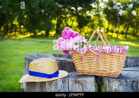 Bel cesto con fiori e cappello si erge su un legno moncone Foto Stock