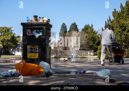 Pinner Regno Unito. Aprile 2021. Traboccante bidone dei rifiuti presso il ducklaghetto presso il Memorial Park, Pinner, Middlesex, Regno Unito. L'uomo cammina oltre spingendo pRAM. Foto Stock