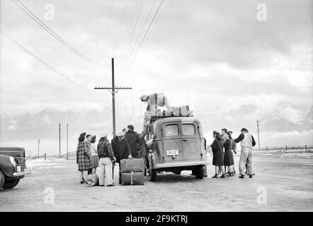 Uomo che carica autobus con bagagli mentre il gruppo di giapponese-americano aspetta di lasciare Manzanar per il trasferimento, Manzanar Relocation Center, California, USA, Ansel Adams, Manzanar War Relocation Center Collection, 1943 Foto Stock