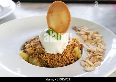 Dessert crumble di mele con mandorle, gelato alla vaniglia e biscotto. Concetto di delicatessen dolce Foto Stock