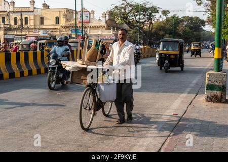 Mysuru, Karnataka, India - Gennaio 2019: Un venditore di strada che cammina con la sua bicicletta su una strada trafficata nella città di Mysore. Foto Stock