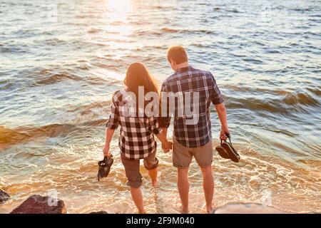 Paio di camminare sulla spiaggia al tramonto Foto Stock