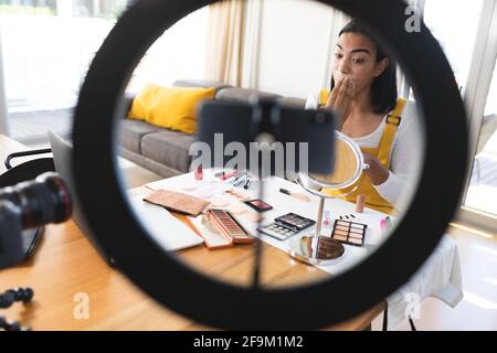 Misto razza transgender donna che fa vlog utilizzando il laptop, smartphone e l'illuminazione mettere sul trucco Foto Stock