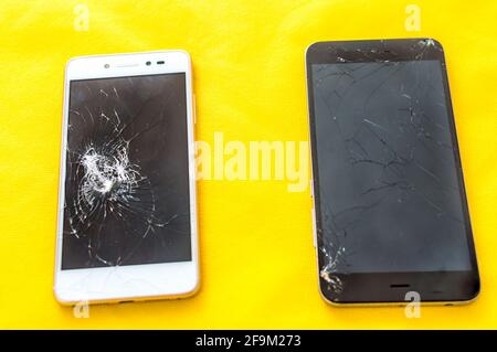 Concetto di telefono rotto. Concetto di riparazione dello smartphone. Due schermi rotti di telefoni cellulari Foto Stock