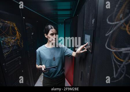 Vita ritratto di donna militare utilizzando il pannello di controllo durante la configurazione dei server nel data center, spazio di copia Foto Stock