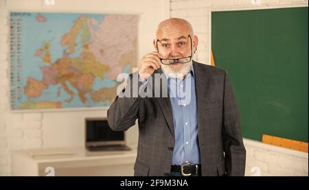 Più strumenti introdotti nelle aule di tutti i giorni. Insegnante di uomo anziano presso la lavagna. Ritorno a scuola. Insegnante di vecchia generazione scolastica. Docente esperto Foto Stock