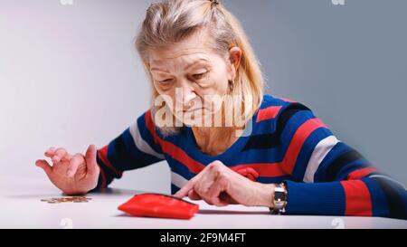 triste povera anziana donna contando monete e guardando un portafoglio vuoto. Foto di alta qualità Foto Stock