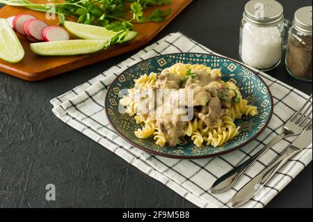 Pasta italiana a grani interi con fegato di pollo arrosto e cipolle servite su un piatto su sfondo marmoreo. Foto Stock