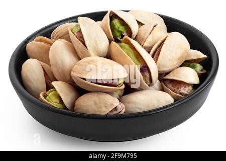 Pistacchi salati in guscio in una ciotola nera in ceramica isolata su bianco. Foto Stock