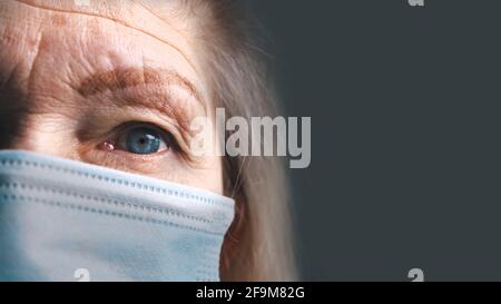 Occhio di una donna anziana con pelle rugosa sotto maschera medica. Primo piano estremo. Foto di alta qualità Foto Stock