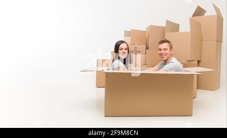 Giovane seduto in una scatola, avendo divertimento dopo lo spostamento nella nuova casa Foto Stock