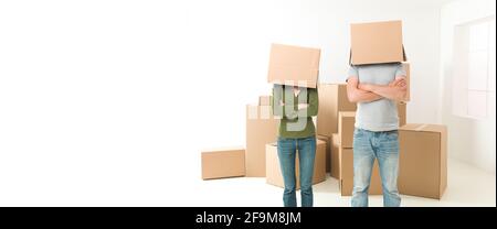 Giovane con scatole sulle loro teste in piedi nella loro nuova casa, con le braccia incrociate contro il petto Foto Stock