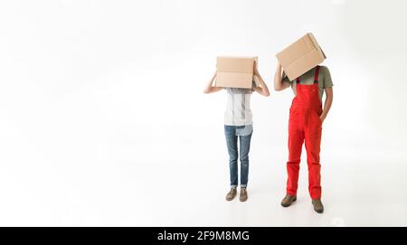 Donna e uomo in piedi e tenendo le scatole di cartone sulla parte superiore dei loro capi, su sfondo bianco. copia di spazio disponibile Foto Stock