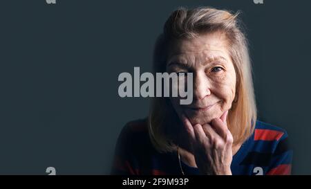 Ritratto di donna anziana con rughe e occhi blu sorridenti alla macchina fotografica. Foto di alta qualità Foto Stock