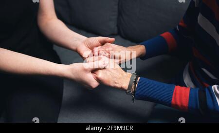 Giovane che tiene le mani di una donna anziana. Foto di alta qualità Foto Stock