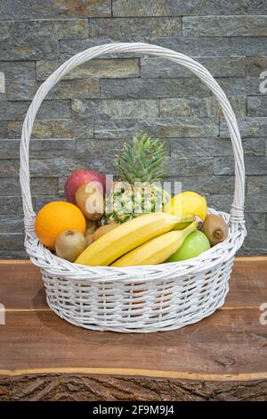 Frutta disposta in un cestino su un tavolo di legno accanto ad un muro di  pietra Foto stock - Alamy