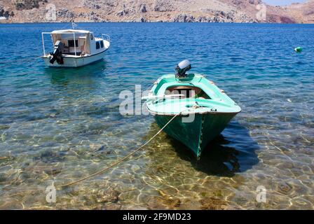 Isola di SYMI Grecia piccole barche ormeggiate in una baia bella cristallo blu chiaro, placida acque incantevole paesaggio marino tipico greco di scena estiva Foto Stock