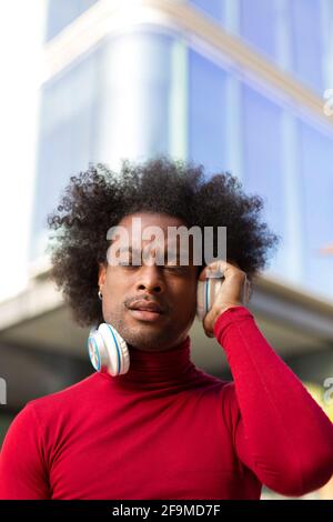 Ritratto di giovane uomo nero con acconciatura afro che ascolta la musica all'aperto. Spazio per il testo. Foto Stock