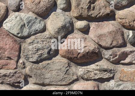 Vecchio muro di pietra stabile con file di pietre di muratura natura. Muratura con modello individuale di mattoni artigianali. Robusta costruzione manuale. Foto Stock
