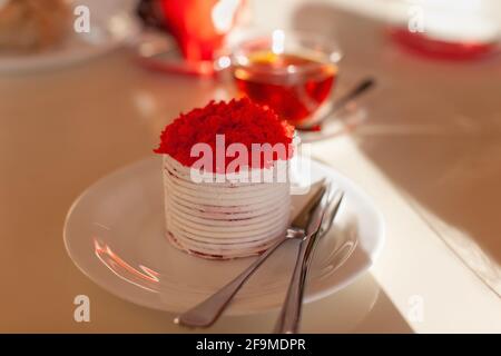 Dessert festivo, torta di velluto rosso sul tavolo al caffè, alla luce del sole. Torta rotonda singola con pan di Spagna imbevuta di sciroppo rosso. Concetto di celebrazione, sw Foto Stock