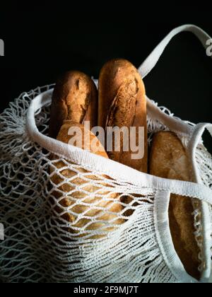 Primo piano di baguette nella borsa della spesa su sfondo nero Foto Stock