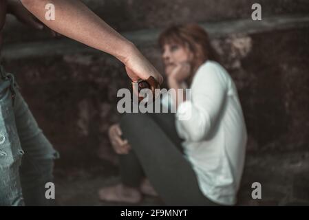 Primo piano della mano dell'uomo con un coltello, colpendo una donna spaventosa, di fronte al muro sporco. Ragazza che soffre di violenza, ha sangue di Th Foto Stock