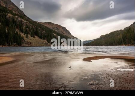 Lunga esposizione di acqua dolce che colpisce la spiaggia del lago Verna, un lago alpino ad alta quota nel Parco Nazionale delle Montagne Rocciose Foto Stock