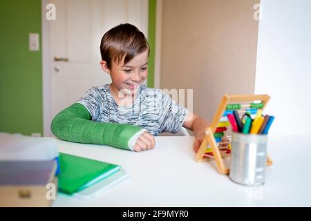 ragazzo freddo con il braccio verde si siede nella sua stanza e impara con la regola di scorrimento con le palle colorate fatte di legno durante homeschooling Foto Stock