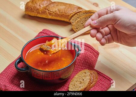 cucchiaio di legno e zuppa in una ciotola di pane Foto Stock