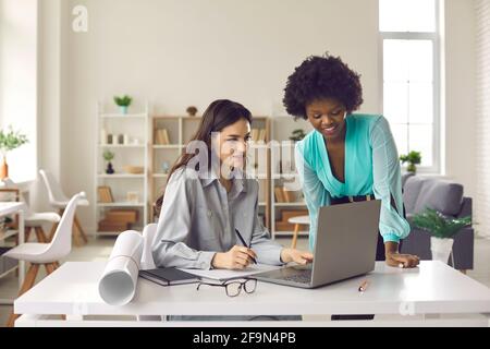 Due giovani architetti o interior designer che lavorano su computer portatili in ufficio Foto Stock