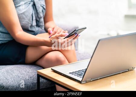 Smartphone e computer portatile. Donna elegante che usa il telefono e il computer. Notifica da sms o e-mail. Giovane ed elegante donna d'affari. Foto Stock