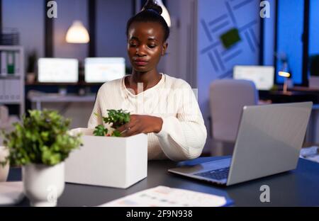 Depresso dipendente licenziato mettendo il suo roba in scatola bianca dal tavolo in ufficio come essere licenziato. Disoccupato che impacchettano le cose a tarda notte, donna che lascia il posto di lavoro a mezzanotte Foto Stock