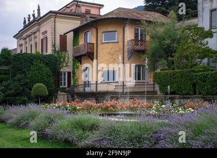 Spruzzi d'acqua dalla fontana sui cespugli fioriti nel giardino di un'antica villa italiana. Foto Stock