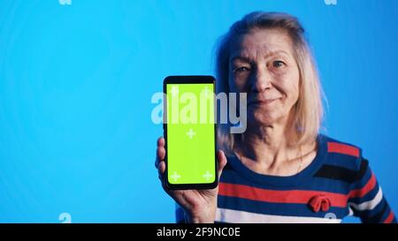 Vecchia donna caucasica che mostra smartphone con schermo verde. Foto di alta qualità Foto Stock