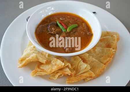 Primo piano: Curry di manzo stufato servito con Roti croccante Foto Stock