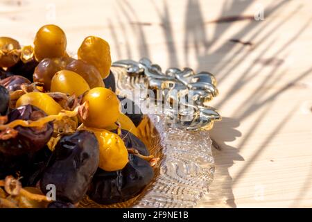 Festa religiosa musulmana di digiuno e mese santo del concetto di Ramadan: Molti frutti di dadè dolci marroni e gialli essiccati su una piastra ornata. Tavolo di legno. Foto Stock