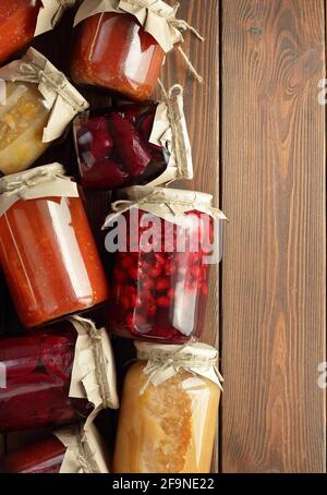 Assortimento di verdure in scatola e frutta-cibo in vasi privi di plastica su tavola rustica di legno, posa piatta, dall'alto vista dall'alto, prodotti in scatola, Foto Stock