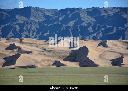 Un paesaggio stratificato di montagne, dune di sabbia e steppa a Khongoryn Els nel Parco Nazionale Gobi Gurvansaikhan, deserto Gobi, Mongolia. Foto Stock