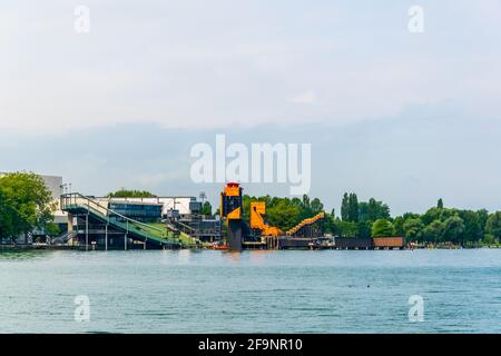 Un teatro all'aperto di colore arancione situato al centro di una striscia verde di alberi che circondano il lago bodensee, vicino a Bregenz, in Austria. Foto Stock