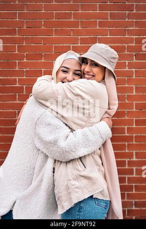 Giovani donne affettive che indossano hijab sorridendo e guardando la macchina fotografica. Foto Stock