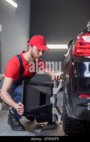 Uomo accovacciato vicino alla ruota anteriore con dispositivo speciale Foto Stock