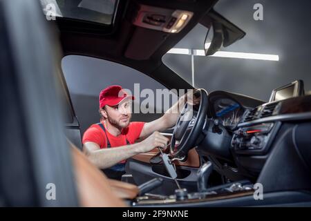 Uomo in tute che fa la manutenzione dell'automobile Foto Stock