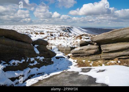 Percorso lungo il bordo settentrionale di Kinder Scout guardando giù sulle brughiere Pennine con insolito mix di neve e sole aprile. Foto Stock