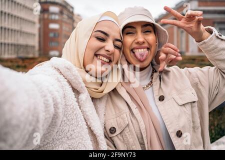 Ragazze allegre che indossano hijab divertirsi e prendere selfie in strada. Foto Stock