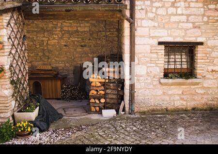 Legna da ardere accatastata sulla strada accanto ad una casa in mattoni in un borgo medievale (Corinaldo, Marche, Italia) Foto Stock