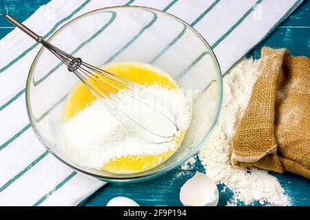 I tuorli d'uovo sbattuti, lo zucchero e la frusta in un recipiente di vetro. Il processo di preparazione dell'impasto per i cialde dolci. Foto Stock